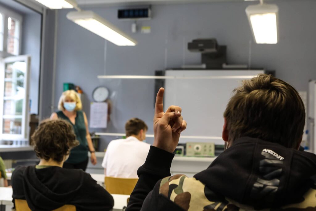 Kinder heben in der Klasse ihre Hände