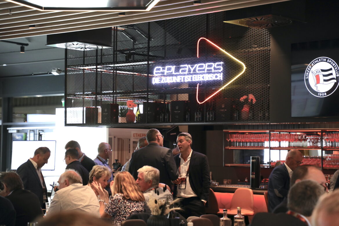 Bild einer Bar, davor Personen wartend. Im oberen beireich des Bildes das Logo der "e-players" in Neon-Schrift.