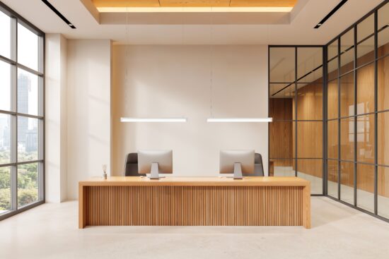 Zwei Pendelleuchten über einem Empfangstresen in einem lichtdurchfluteten Büro mit Holz- und Glaselementen.