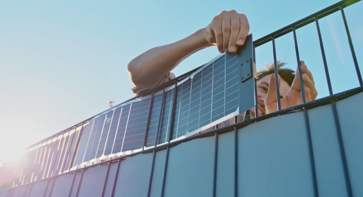 Mann fädelt einen Sunbooster Vertical Solarstreifen in einen Zaun ein.