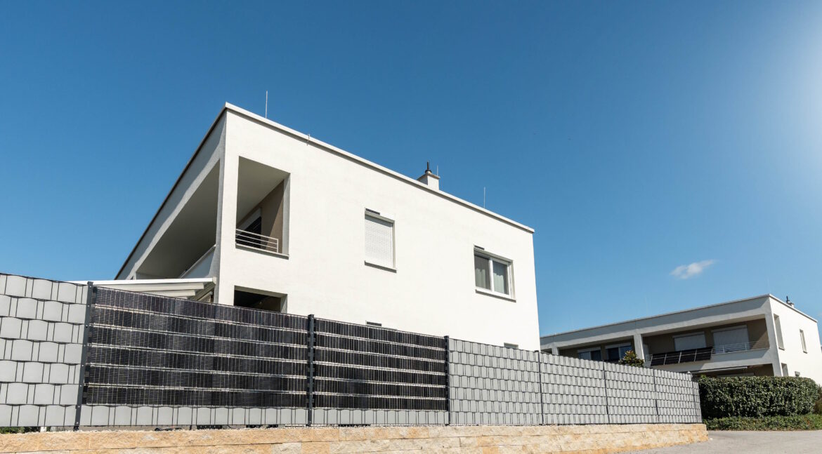 Moderner Wohnbau mit installiertem Sunbooster Vertical Solarzaun als Sichtschutz und Stromerzeugung.