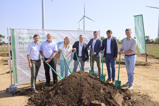Gruppenfoto der Projektpartner mit Spaten beim Spatenstich für das Agri-PV-Hybridkraftwerk in Parndorf, Windräder im Hintergrund.