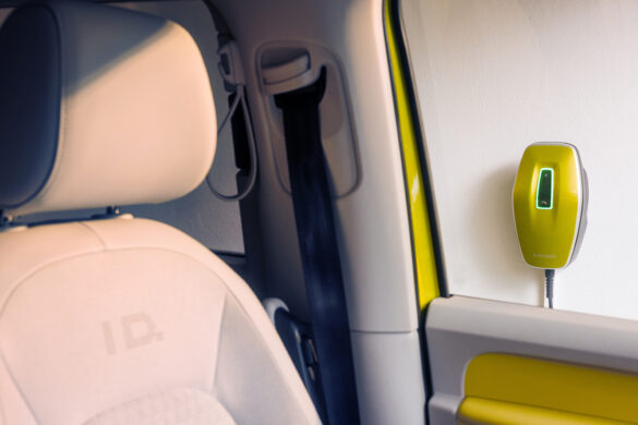 Innenansicht eines Elektroautos mit Blick auf die gelb-grüne AMTRON® 4You 500 Wallbox an der Wand.