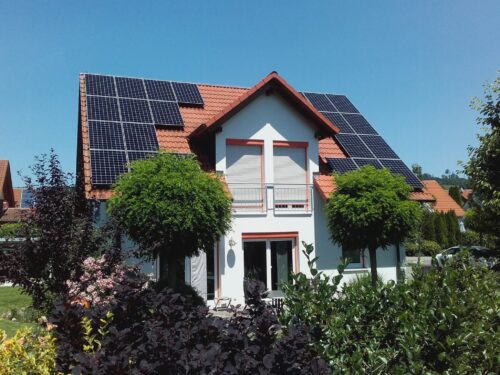Einfamilienhaus mit Photovoltaikanlage auf dem Dach an einem sonnigen Tag.