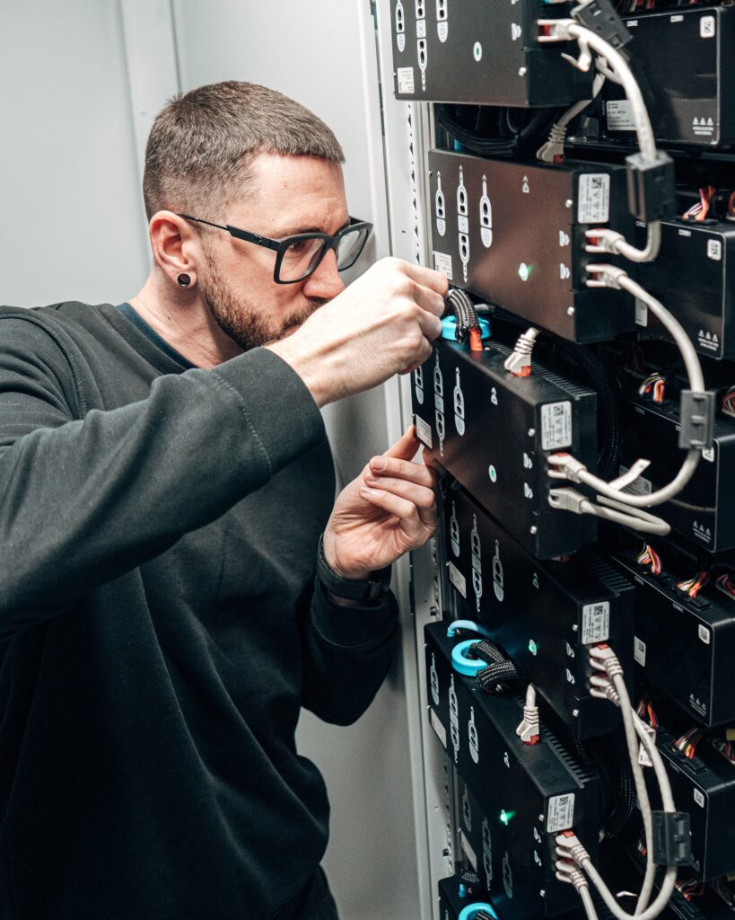 Techniker arbeitet im Inneren an Batteriemodulen eines Energiespeichers.