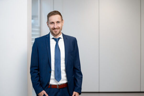 Porträt von Jürgen Hürner, Geschäftsführer der Stadtwerke Amstetten, im blauen Anzug vor heller Wand.