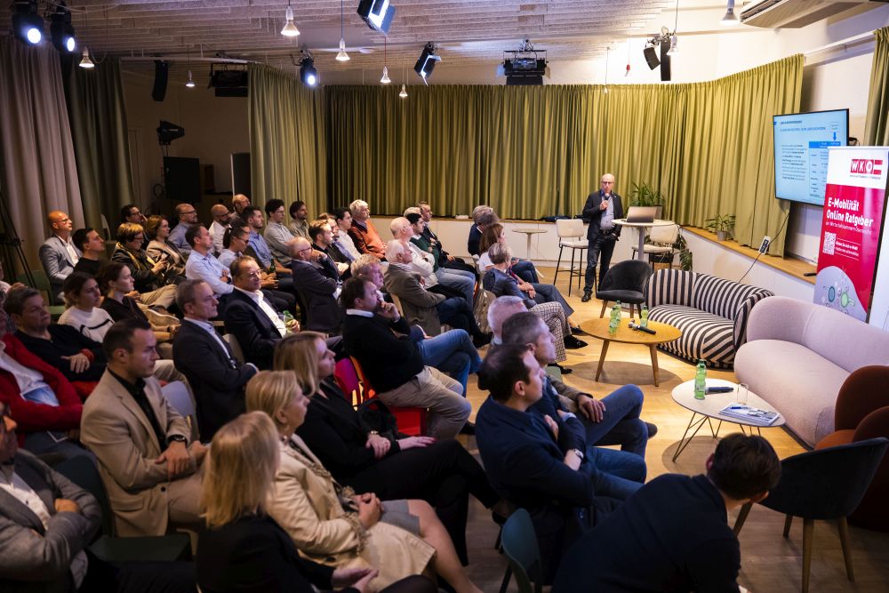 Ein gefüllter Veranstaltungsraum mit zahlreichen Zuhörer:innen, die einem Vortrag über Ladeinfrastruktur und Elektromobilität aufmerksam folgen.