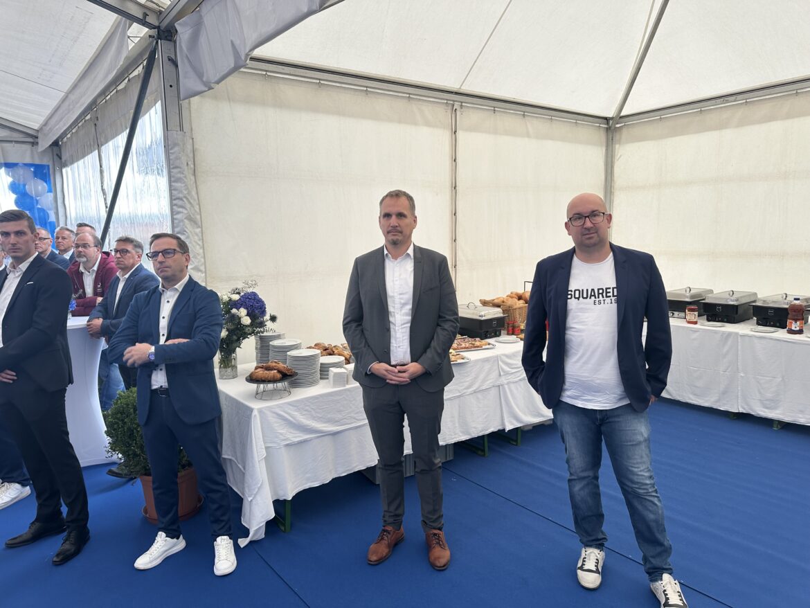 Gäste und Partner stehen vor dem Buffet im Festzelt der Eröffnung.