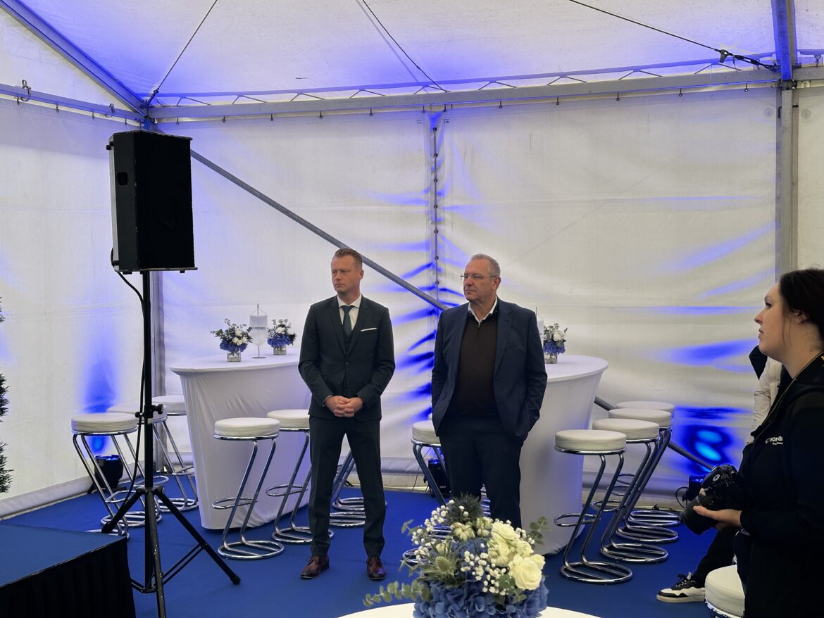 Ehrengäste und Führungskräfte stehen im Festzelt der Eröffnungsfeier.