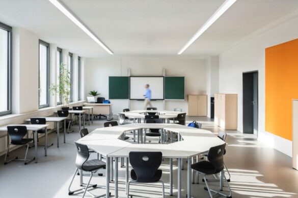 Helles Klassenzimmer mit modernen LED-Lichtbändern, flexibler Möblierung und farblich gestalteten Wänden.