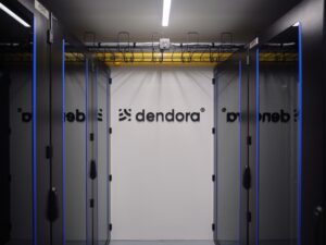 Serverraum im dendora Container mit mehreren Racks und sichtbarem Logo an der Rückwand.