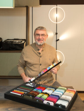 Christian Ipsmiller hält Farbmuster und Leuchtenmaterialien im Prolicht Atelier in Wien in der Hand.