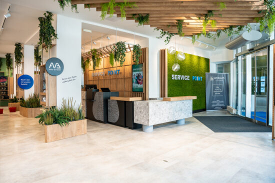 Innenansicht des Service Points mit Beratungsbereich, Holz- und Pflanzenelementen.