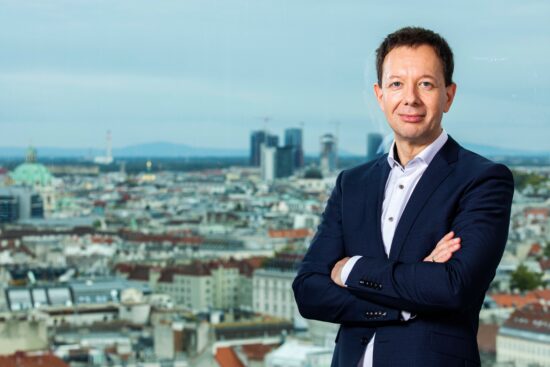Porträt von Karl Gruber, GF von Wien Energie vor einer Wiener Stadtansicht.