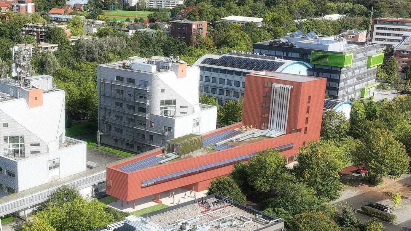Luftaufnahme eines modernen Forschungsgebäudes mit roter Fassade und Solaranlagen auf dem Dach.
