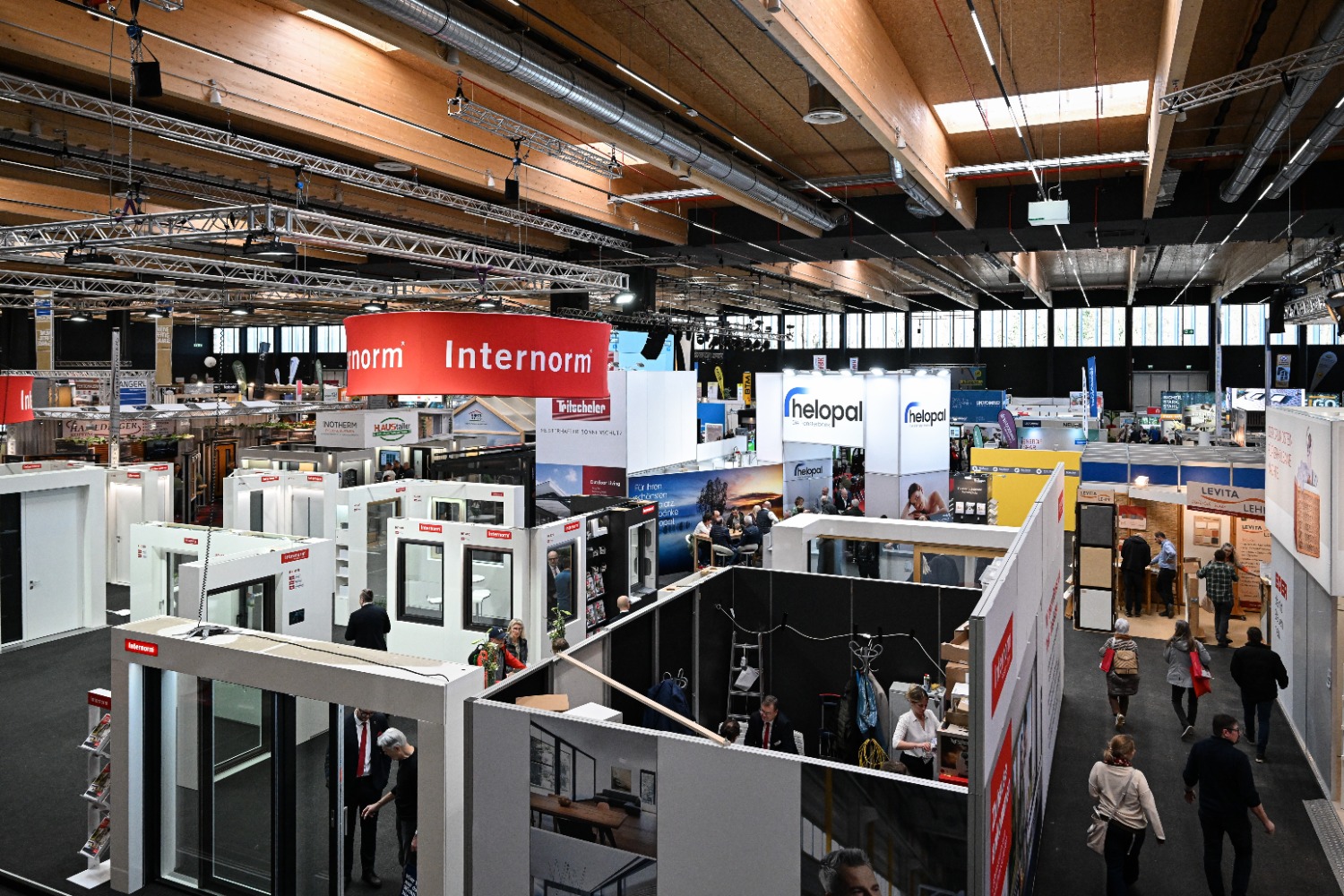 Vogelperspektive auf eine weitläufige Messehalle mit dem markanten roten Internorm-Rundstand im Vordergrund und zahlreichen weiteren Ausstellern im Hintergrund.