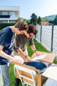 Zwei Personen prüfen Unterlagen beim Auspacken eines Sunbooster-Sets im Garten.