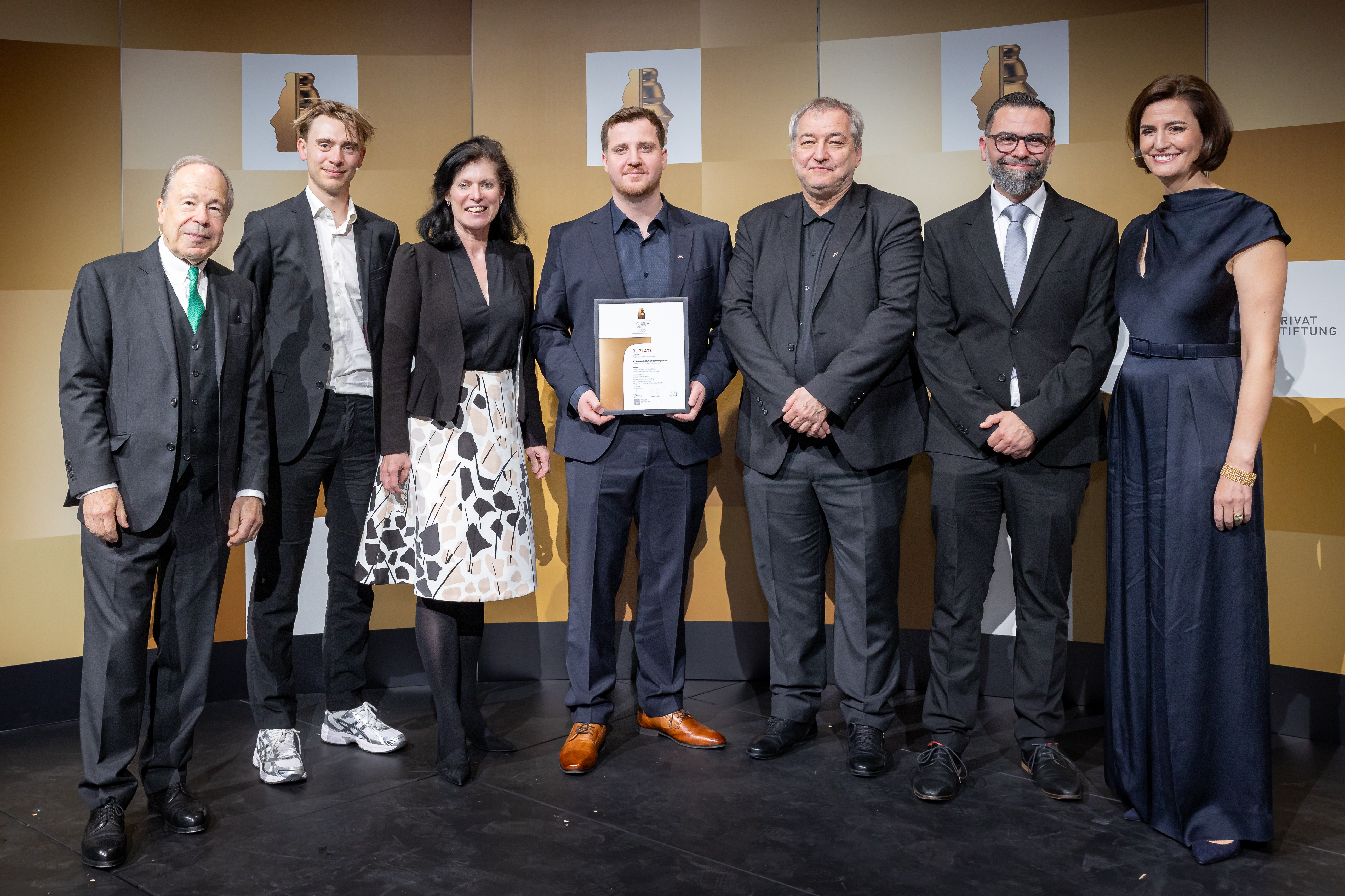 Sieben Personen stehen bei der Houskapreis-Verleihung auf der Bühne und präsentieren eine Urkunde.