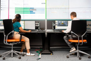 Zwei Personen überwachen Energiedaten an mehreren Bildschirmen.
