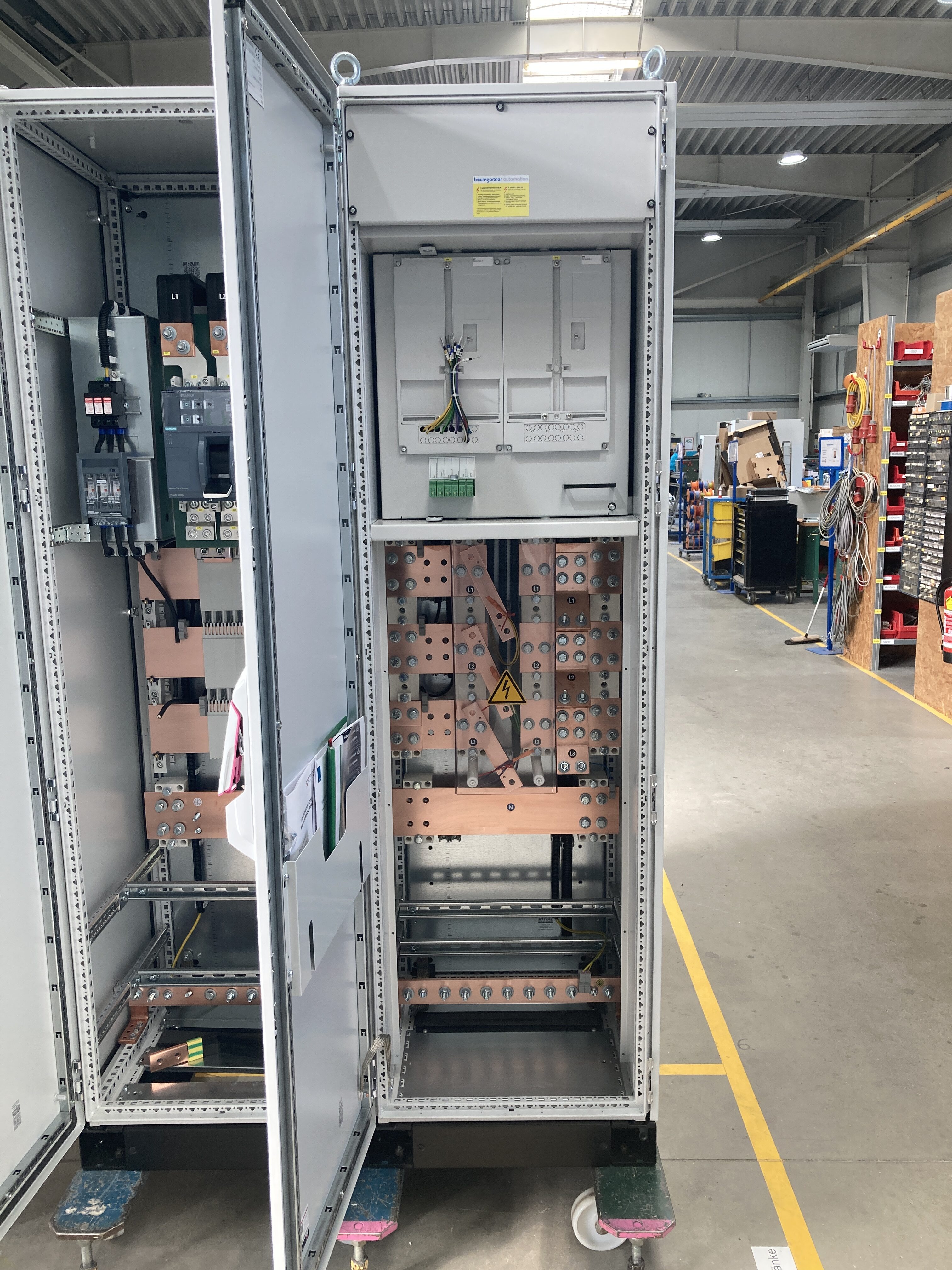 Geöffneter Wandlermessschrank mit Kupferschienen und Messkomponenten in der Produktionshalle.