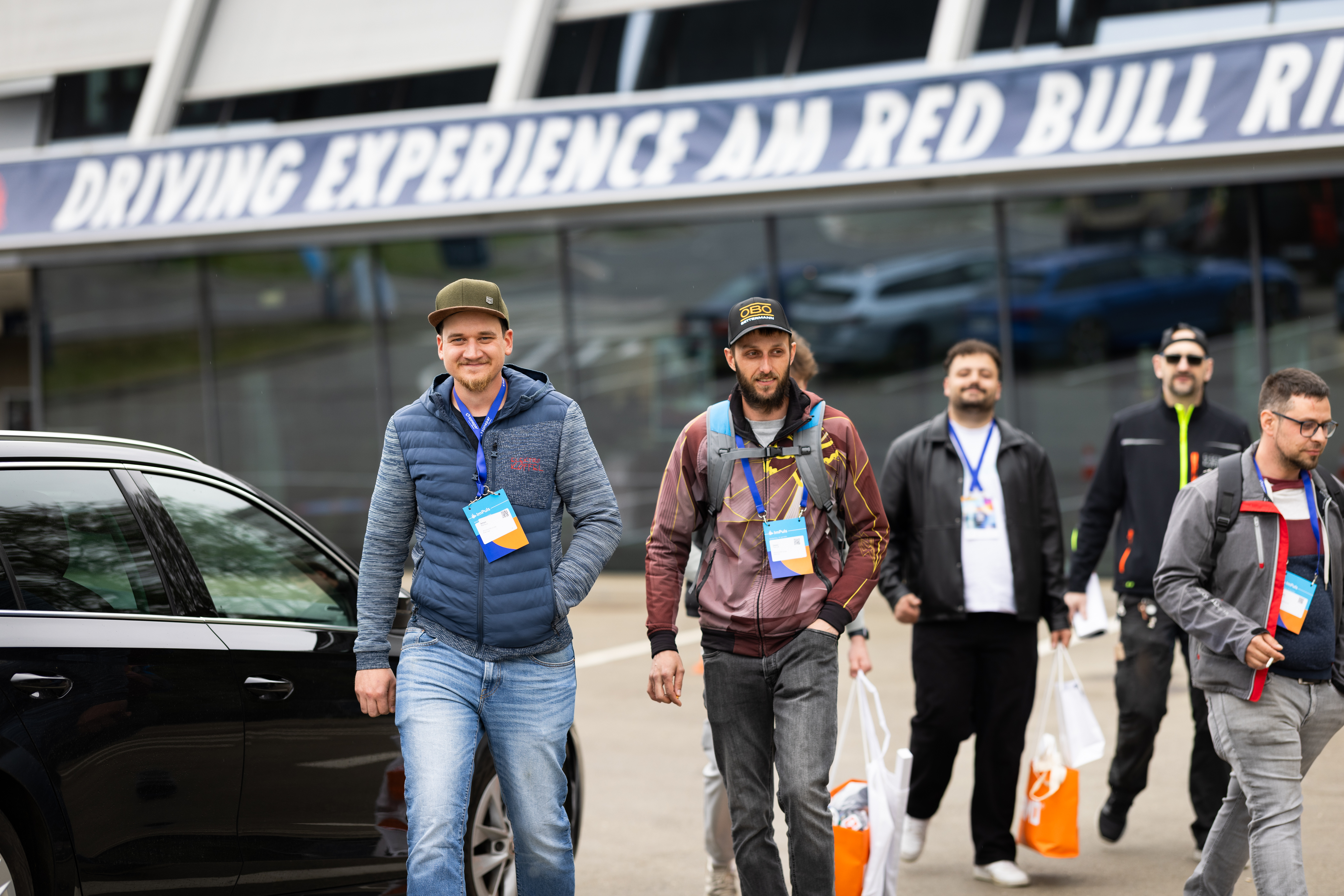Besucher gehen mit Taschen vor dem Red Bull Ring Geländ