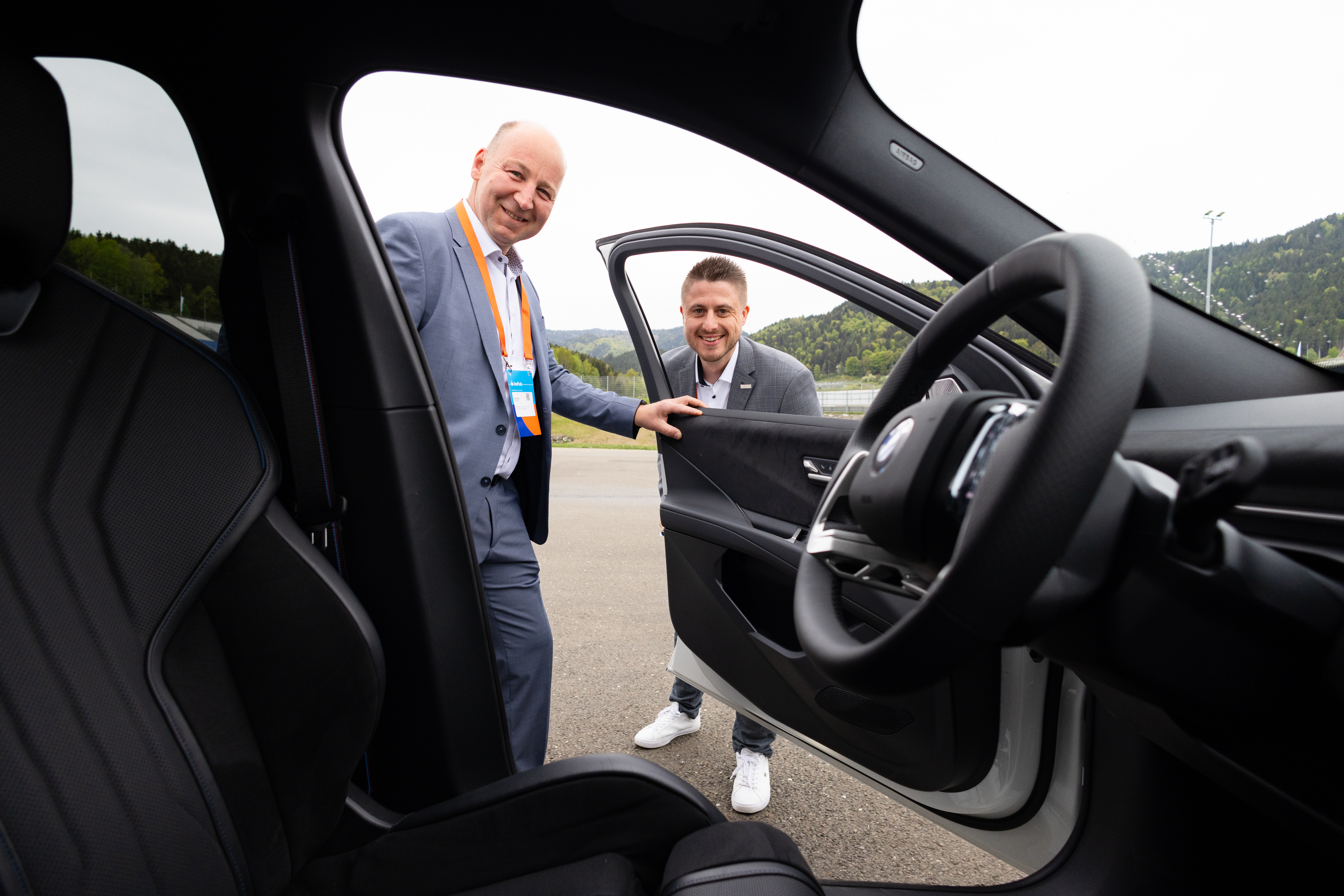 Zwei Männer betrachten ein Fahrzeug durch die geöffnete Fahrertür.