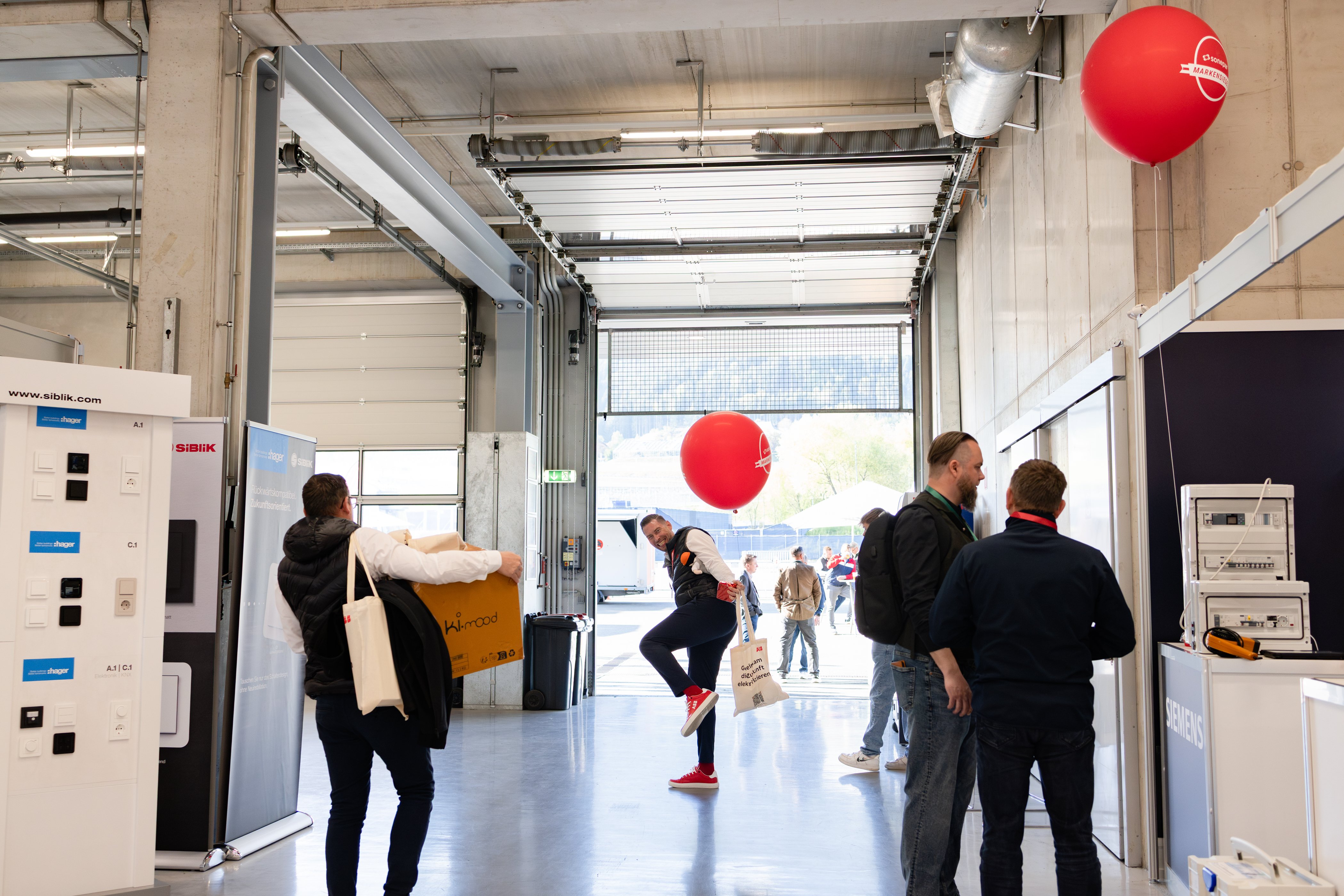 Besucher balanciert spielerisch mit einem roten Ballon in einer Messehalle.