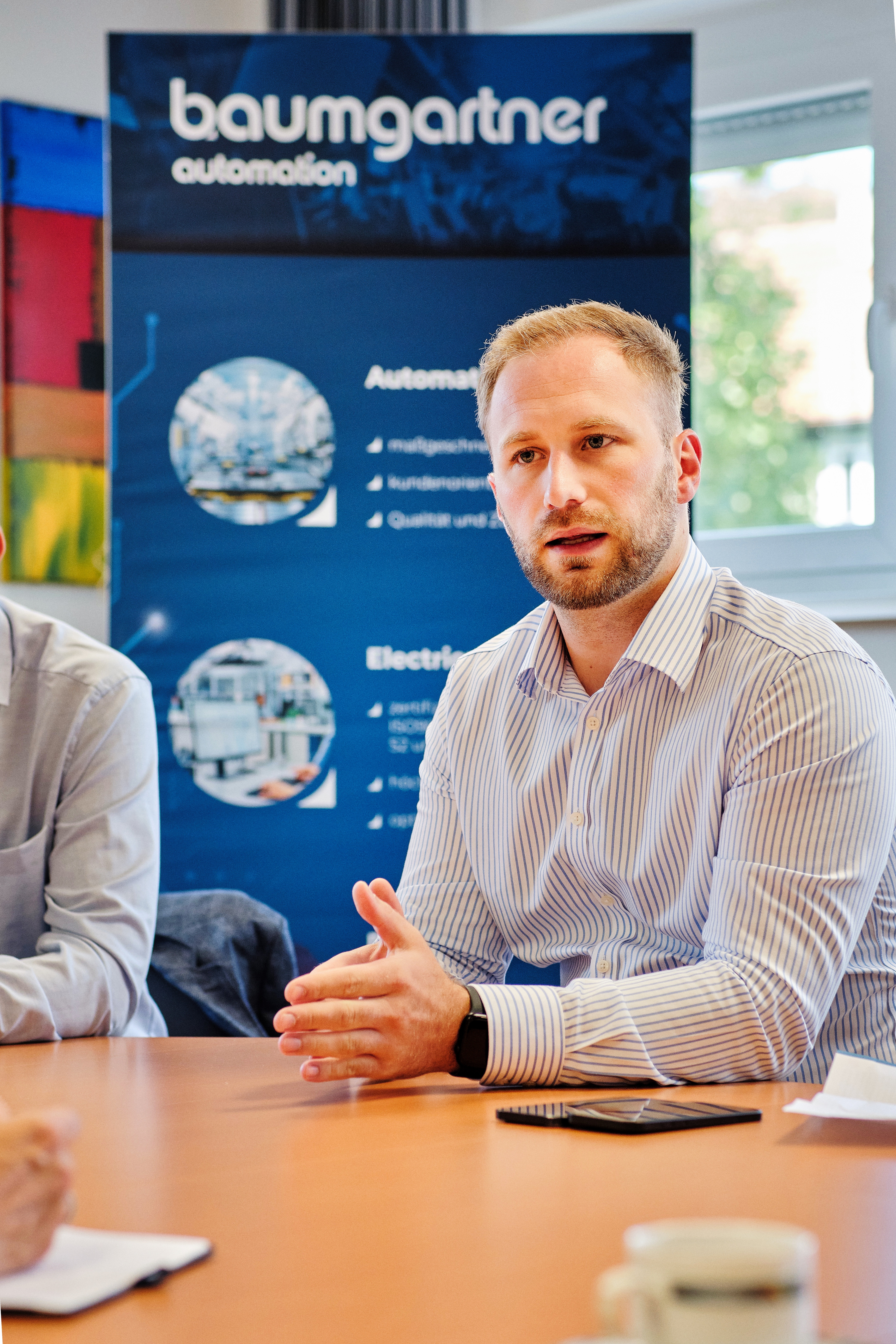 Daniel Hochschartner von Baumgartner Automation sitzt im Besprechungsraum und erklärt Digitalisierungs- und Automatisierungslösungen.
