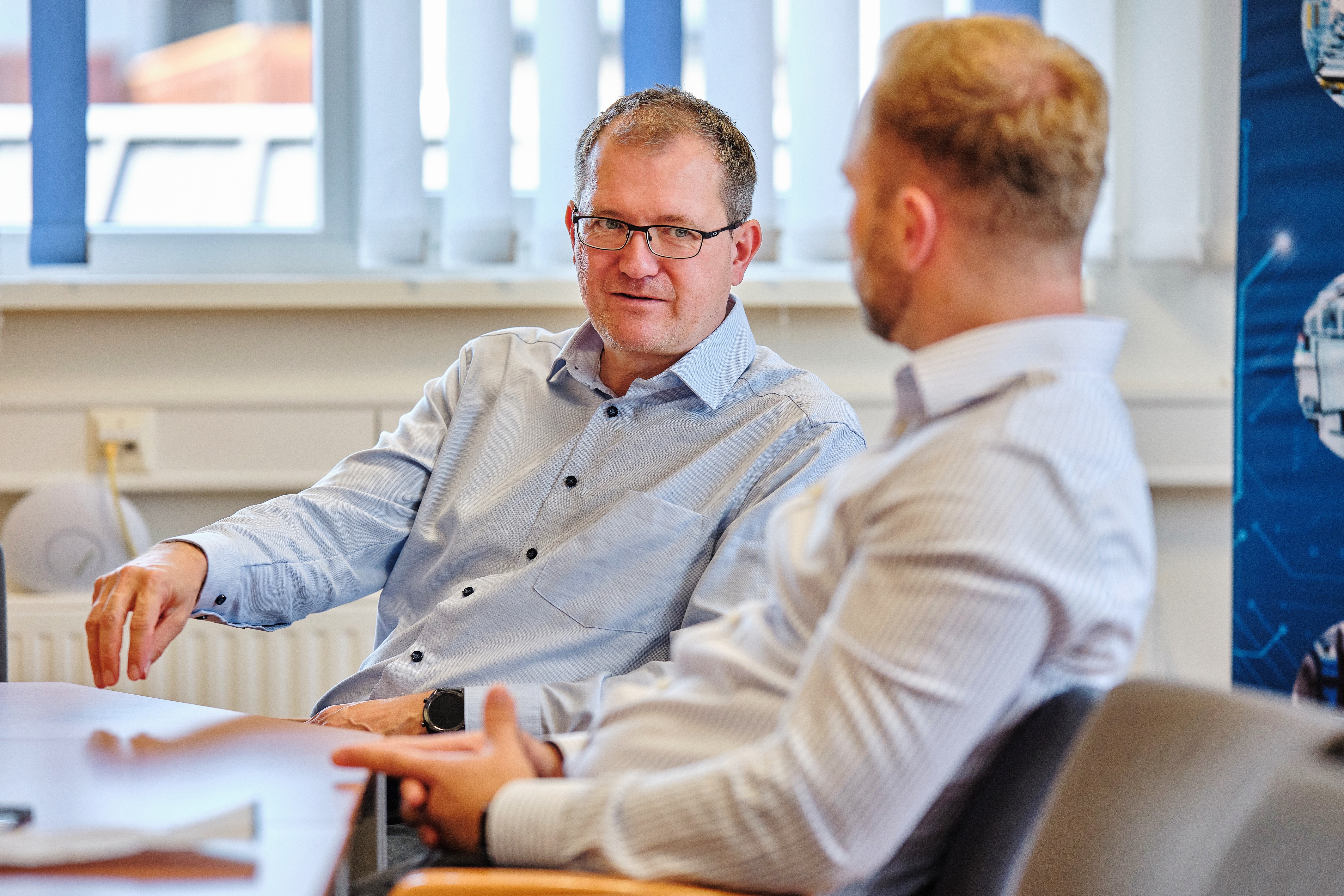 Zwei Mitarbeiter von Baumgartner Automation diskutieren im Besprechungsraum über technische Lösungen und Projekte.