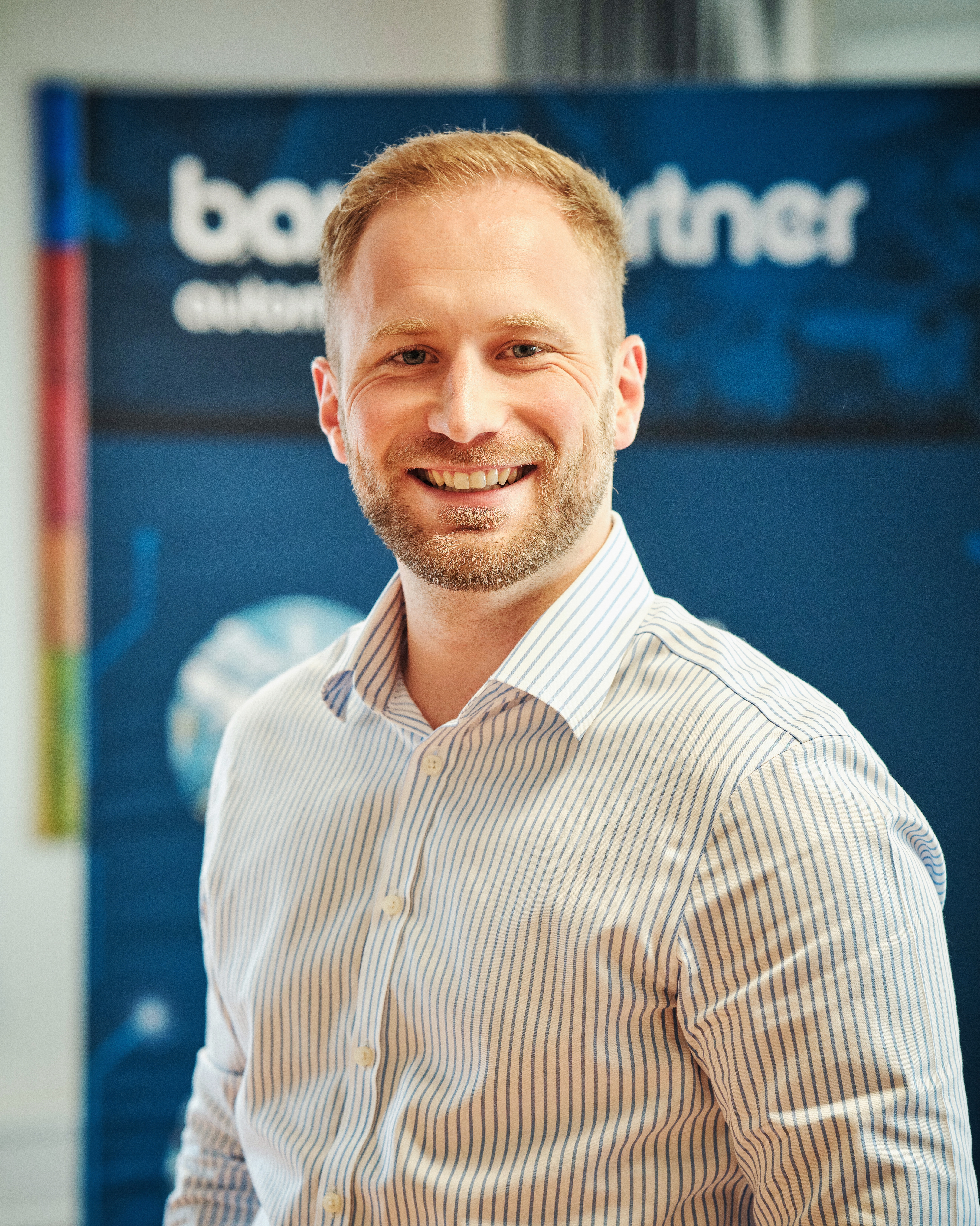 Portrait von Daniel Hochschartner vor einem Unternehmensbanner von Baumgartner Automation.