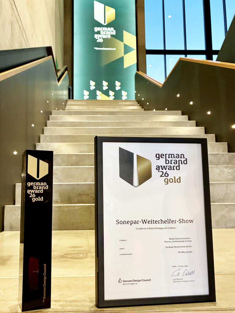 German Brand Award GOLD und Urkunde vor der Kulisse der Preisverleihung.