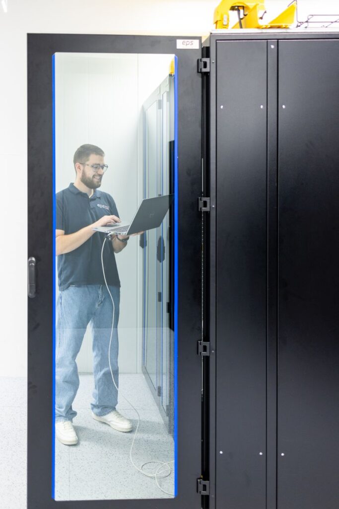 EPS-Techniker überprüft eine USV-Anlage mit einem Laptop im Serverraum.