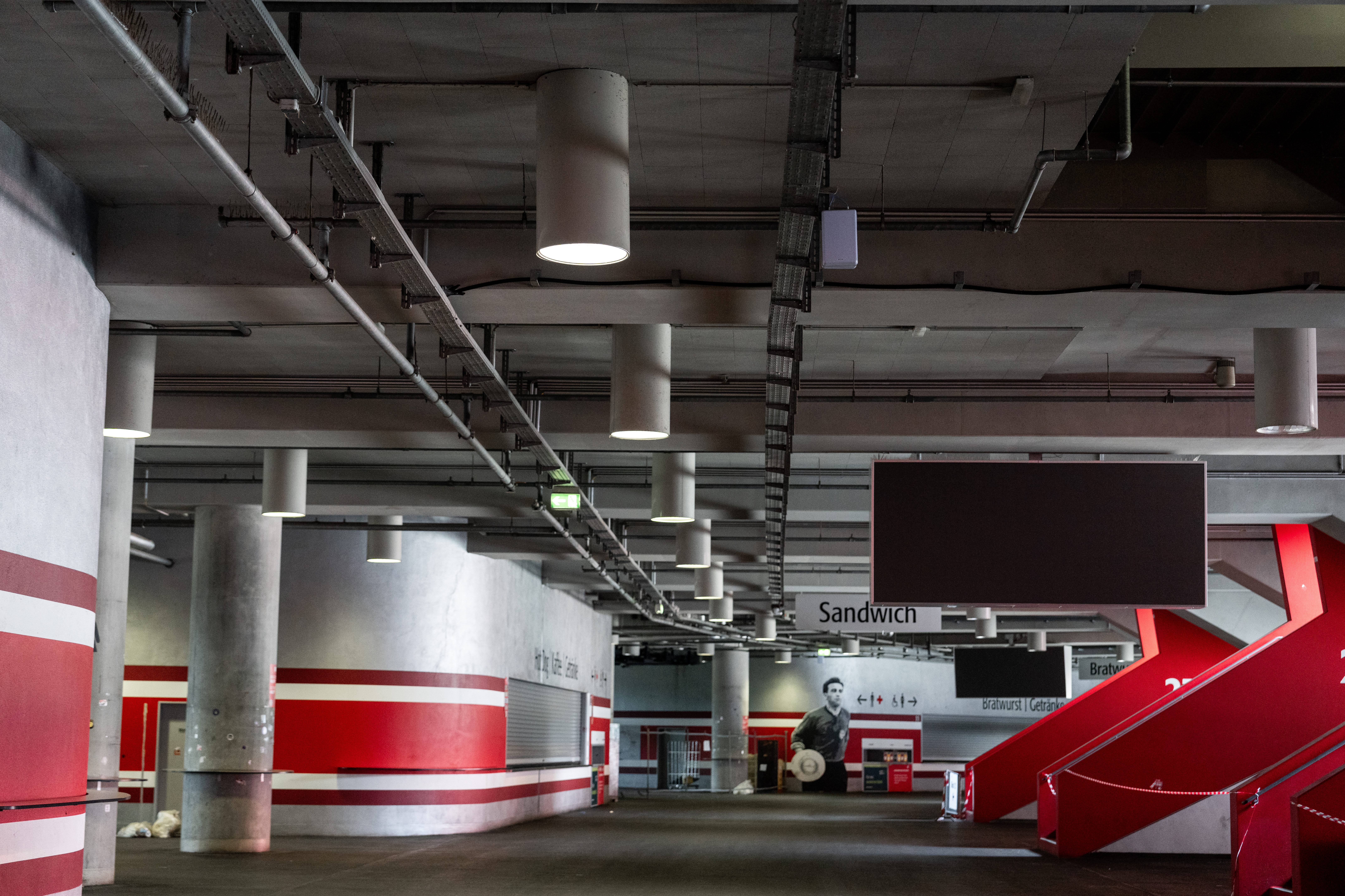 Beleuchteter Umlaufbereich der Allianz Arena mit neuer Ledvance-Lichttechnik und roten Treppenaufgängen.