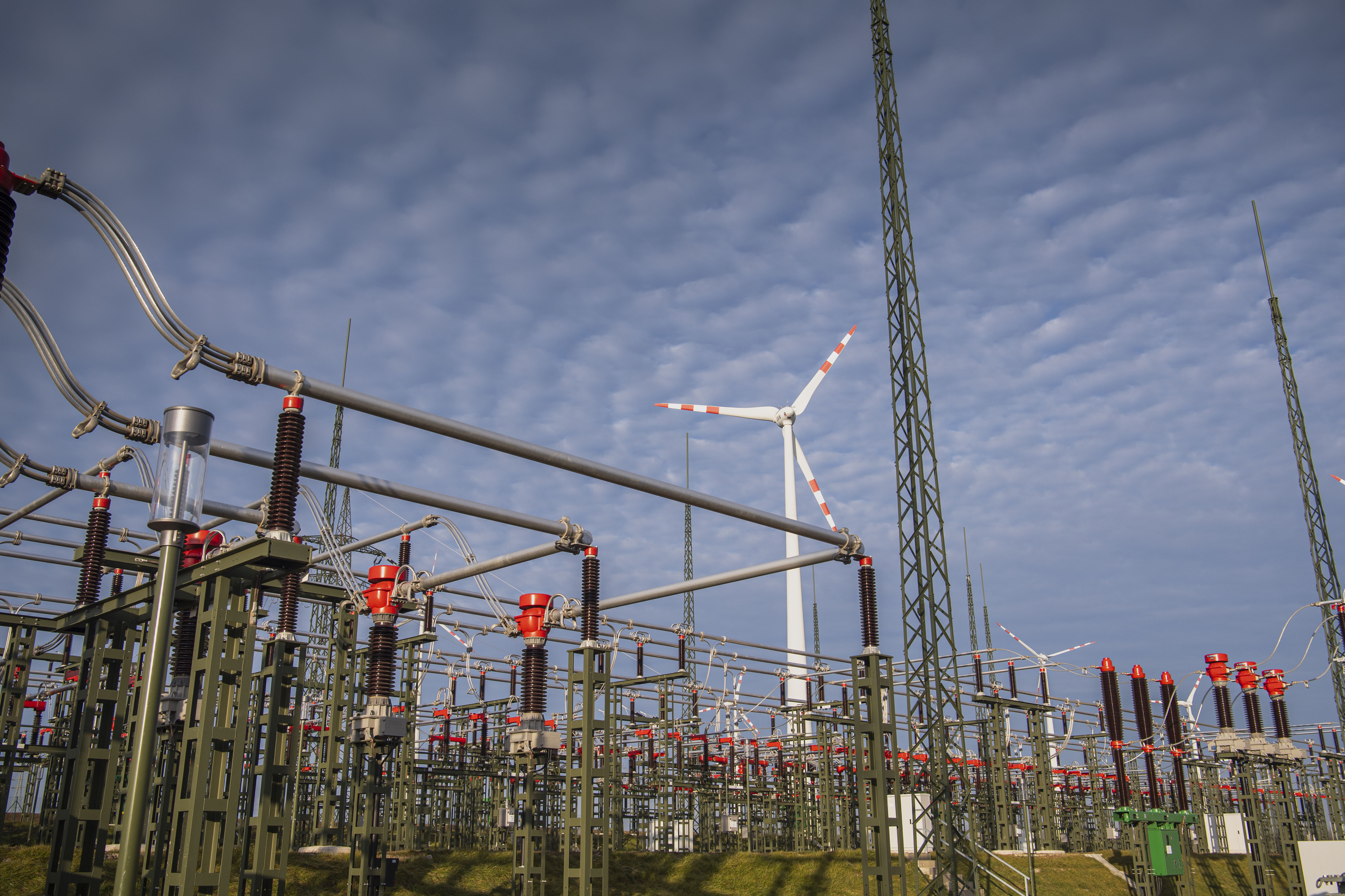 Umspannwerk von Netz NÖ in Ketlasbrunn mit elektrischen Anlagen und Windkraftanlage im Hintergrund.