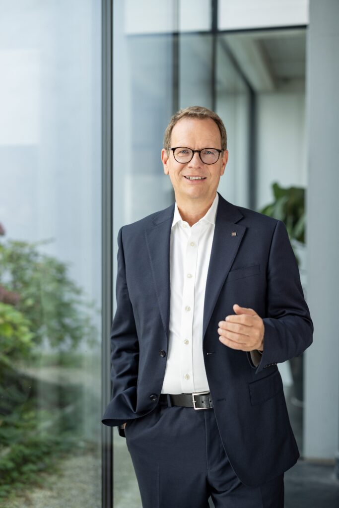EVN Vorstandssprecher Stefan Szyszkowitz im dunklen Anzug vor einer modernen Glasfassade.