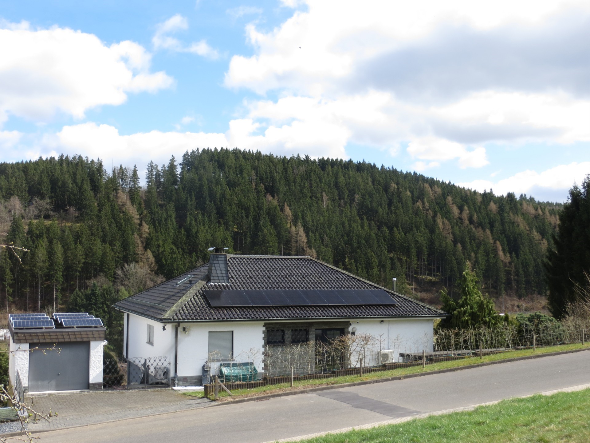 Einfamilienhaus mit Photovoltaikmodulen auf Dach und Garage